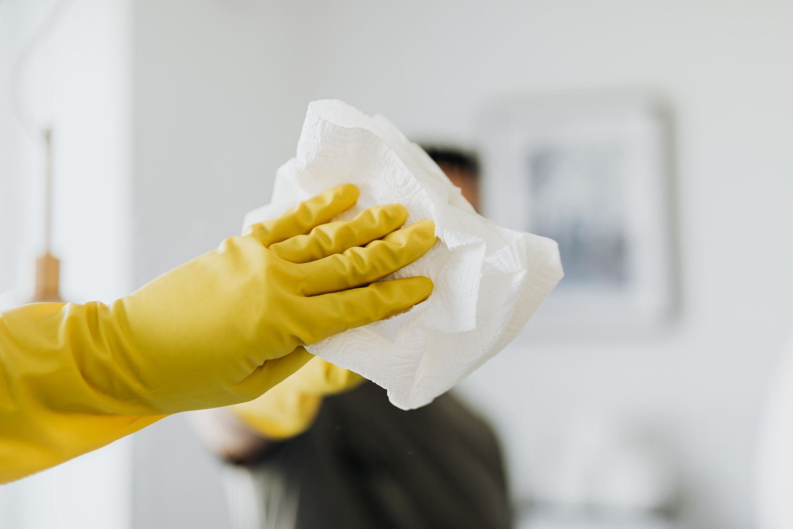 Homme non reconnaissable nettoyant un miroir avec des gants